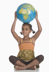 African girl (6-7) with globe on head, portrait - WWF00922