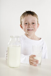 Junge (6-7) hält ein Glas Milch, lächelnd, Porträt - RBF00125