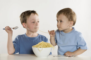 Zwei Jungen (6-7) (2-3) essen Spaghetti, teilen sich Nudeln, Porträt - RBF00124
