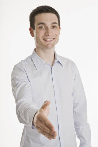 Geschäftsmann streckt seine Hand aus, lächelnd, Porträt, lizenzfreies Stockfoto