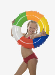 Mädchen (10-11) im Bikini schaut durch einen schwimmenden Reifen, Porträt - WWF01023