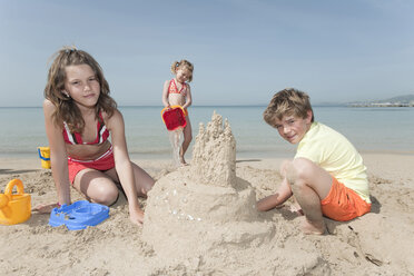 Spain, Mallorca, Children building sandcastle on beach - WESTF12708