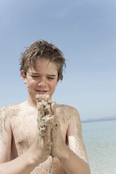 Spanien, Mallorca, Junge (8-9) mit sandigen Händen beim Spielen am Strand - WESTF12644