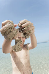 Spanien, Mallorca, Junge (8-9) mit sandigen Händen beim Spielen am Strand - WESTF12643