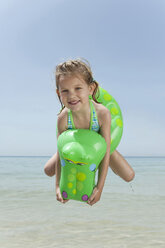 Spanien, Mallorca, Mädchen (4-5) am Strand mit Schlauchboot, springend - WESTF12641