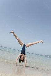 Spanien, Mallorca, Mädchen (10-11) macht Handstand am Strand - WESTF12623