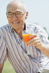 Spanien, Mallorca, Senior Mann hält Glas mit Orangensaft, Porträt - WESTF12948