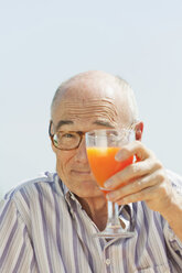 Spain, Mallorca, Senior man holding glass with orange juice, portrait - WESTF12947