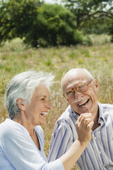 Spain, Mallorca, Senior couple sitting on grass, having fun, portrait - WESTF12939