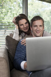 Germany, Hamburg, Couple in living room using laptop - WESTF13116