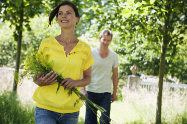 Deutschland, Hamburg, Pärchen im Garten, Frau hält Blumenstrauß - WESTF13100