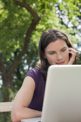 Deutschland, Hamburg, Frau benutzt Laptop im Garten - WESTF13059