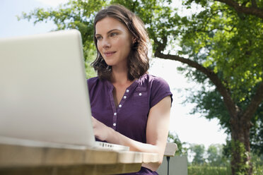 Deutschland, Hamburg, Frau benutzt Laptop im Garten - WESTF13058