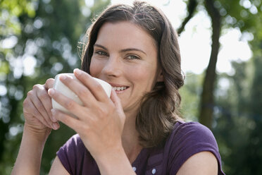 Deutschland, Hamburg, Frau hält Tasse Kaffee, Porträt, Nahaufnahme - WESTF13052