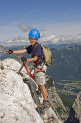 Deutschland, Garmisch-Partenkirchen, Alpspitz, Junge (10-11) klettert auf Leiter an Felswand, lächelnd, Porträt - RNF00006
