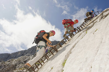 Deutschland, Garmisch-Partenkirchen, Alpspitz, Mutter und Söhne (10-11), (12-13) klettern auf einer Leiter an einer Felswand - RNF00005