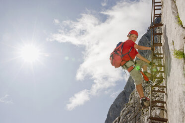 Deutschland, Garmisch-Partenkirchen, Alpspitz, Junge (12-13) klettert auf Leiter an Felswand, Tiefblick - RNF00003