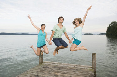 Deutschland, Bayern, Starnberger See, Junge Leute springen auf Steg, lachend, Porträt - RNF00078