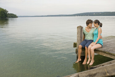 Germany, Bavaria, Starnberger See, Young couple sitting on jetty - RNF00068