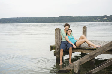 Germany, Bavaria, Starnberger See, Young couple sitting on jetty - RNF00067