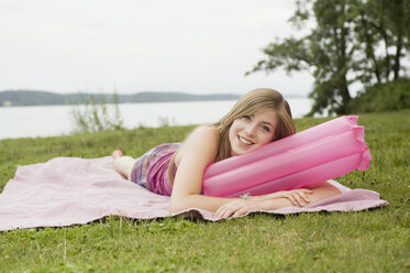 Deutschland, Bayern, Starnberger See, Junge Frau auf Decke im Park liegend, lächelnd, Porträt - RNF00018