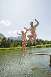 Italy, South Tyrol, Men jumping into lake, fooling about - WESTF13353