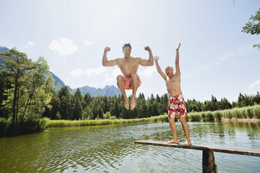 Italy, South Tyrol, Men jumping into lake, fooling about - WESTF13352