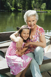 Italien, Südtirol, Großmutter und Enkelin (8-9) im Ruderboot sitzend, lächelnd, Porträt - WESTF13315