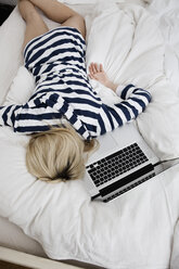 Deutschland, Berlin, Junge Frau im Bett liegend, Laptop daneben, Blick von oben - WESTF13480