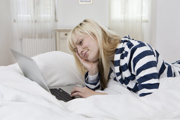 Deutschland, Berlin, Junge Frau im Bett liegend, mit Laptop - WESTF13479