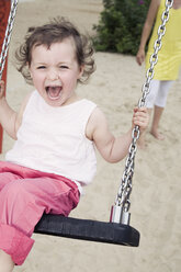 Germany, Berlin, Girl (3-4) at playground, sitting on swing, laughing, portrait, close-up - WESTF13601