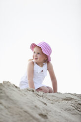 Germany, Girl (4-5) kneeling on sand dune, looking away, portrait - MAEF01873