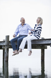 Germany, Bavaria, Starnberger See, Senior couple sitting on jetty, laughing, portrait - MAEF01904