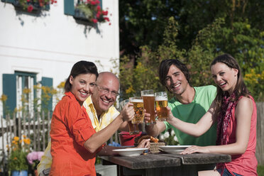 Deutschland, Bayern, Freunde trinken Bier im Garten, stoßen mit Gläsern an - WESTF13270