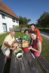 Deutschland, Bayern, Menschen am Tisch im Garten bei der Essenszubereitung - WESTF13266