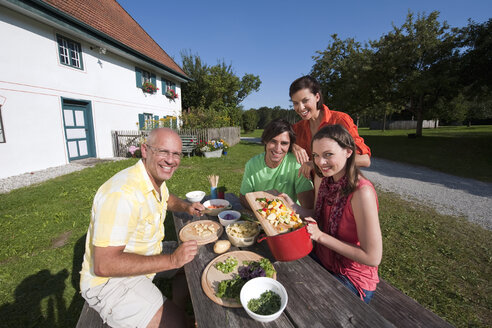 Deutschland, Bayern, Menschen am Tisch im Garten bei der Essenszubereitung - WESTF13265