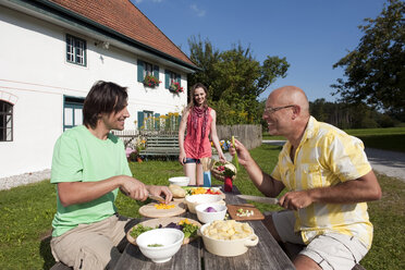 Deutschland, Bayern, Zwei Männer am Tisch im Garten bei der Essenszubereitung - WESTF13261