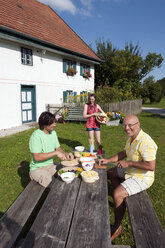 Deutschland, Bayern, Zwei Männer am Tisch im Garten bei der Essenszubereitung - WESTF13260