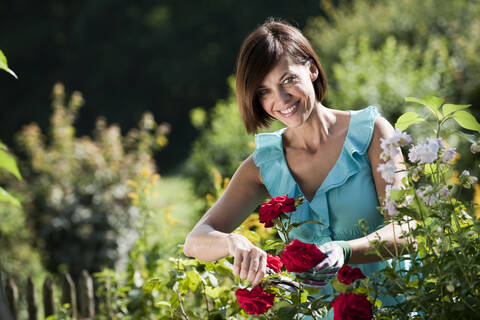 Deutschland, Bayern, Frau schneidet Blumen im Garten, lizenzfreies Stockfoto