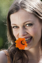 Deutschland, Bayern,Junge Frau hält Blume, lächelnd, Nahaufnahme - WESTF13252