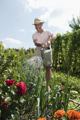 Deutschland, Bayern, Senior Mann gießt Blumen, lachend, Porträt - WESTF13234