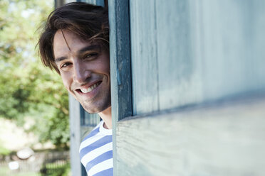 Germany, Bavaria, Man standing next to barn door, smiling, portrait - WESTF13227