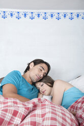 Germany, Bavaria, Young couple lying in bed - WESTF13201