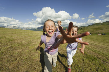 Italy, Seiseralm, Mother and daughters (6-7), (8-9) running in meadow, laughing, portrait - WESTF13431