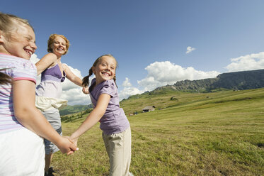 Italy, Seiseralm, Mother and children (6-7), (8-9) dancing in meadow, laughing, portrait - WESTF13428