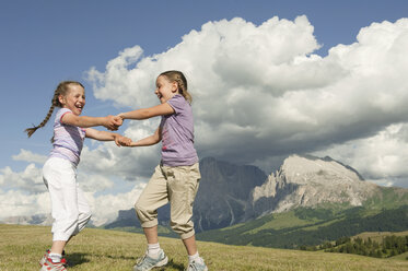 Italy, Seiseralm, Girls (6-7), (8-9) dancing in meadow - WESTF13427