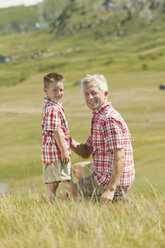 Italy, Seiseralm, Grandfather and grandson (6-7) in field - WESTF13394