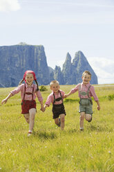 Italien, Seiseralm, Drei Kinder (4-5), (6-7), (8-9) laufen im Feld - WESTF13387