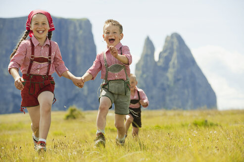 Italien, Seiseralm, Drei Kinder (4-5), (6-7), (8-9) laufen im Feld - WESTF13386