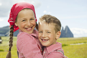 Italien, Seiseralm, Junge (6-7) und Mädchen (8-9) im Feld, sich umarmend, lächelnd, Porträt, Nahaufnahme - WESTF13383
